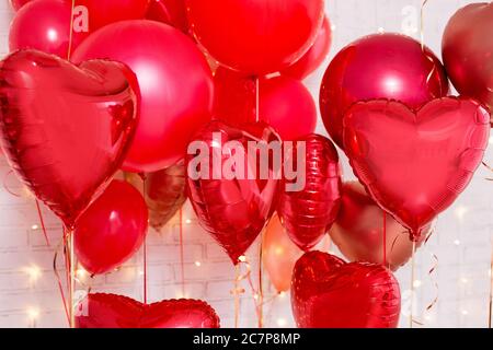 San Valentino sfondo - palloncini a forma di cuore rosso su muro di mattoni bianchi Foto Stock