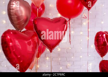 Decorazione di San Valentino - gruppo di palloncini a forma di cuore rosso su sfondo bianco parete Foto Stock