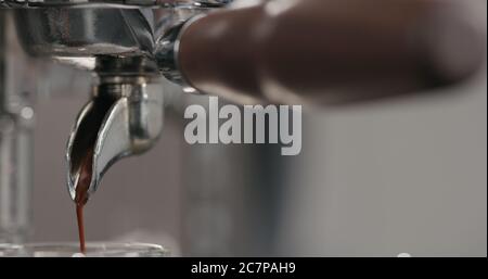 estrazione della shot di espresso con portafiltro a beccuccio singolo dalla macchina da caffè primo piano Foto Stock