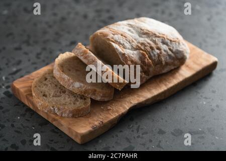 Ciabatta rustica a fette con farina di segale su tavola di oliva Foto Stock
