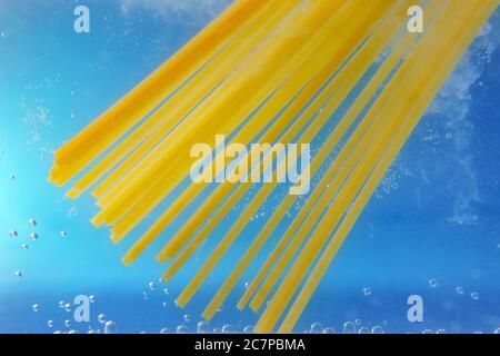 Gettando la pasta pappardelle in acqua bollita, primo piano. Fuoco selettivo, cottura della pasta Foto Stock