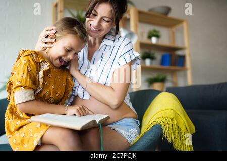 Madre con sua figlia carina la lettura di un libro a casa Foto Stock