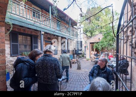 La nuova normalità, presto un Sabato mattina a Mudgee, Australia persone stand e sedersi a distanze appropriate e bere caffè in un cortile aperto Foto Stock