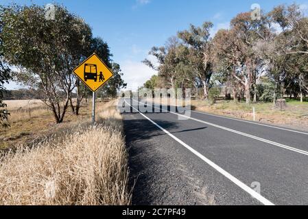 Un cartello di segnalazione per la fermata dell'autobus di campagna accanto a una lunga strada curva vuota vicino a Mudgee nel centro-ovest del New South Wales, Australia Foto Stock