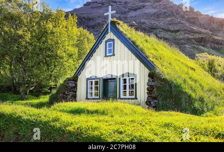 Vista pittoresca della chiesa di Hofskirkja in cima al tappeto erboso durante il tramonto. Ubicazione: Villaggio di Hof, Skaftafell, Parco Nazionale di Vatnajokull, Europa. Foto Stock
