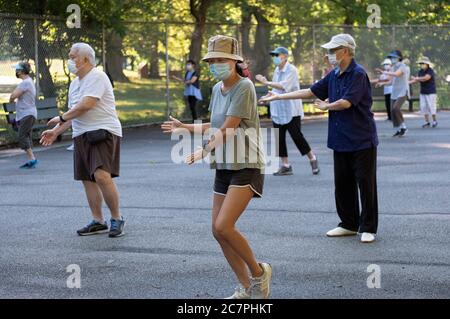 Uomini e donne di varie età ed etnie frequentano una lezione di Tai Chi mattina di distanza sociale e indossare maschere chirurgiche. In Queens, New York City. Foto Stock