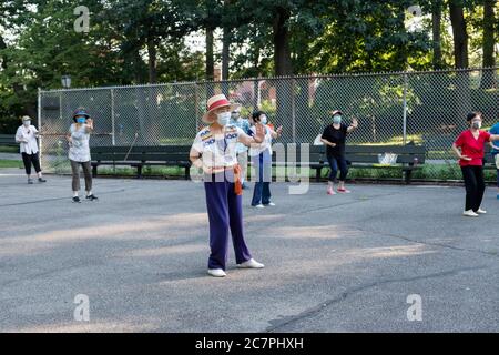 Uomini e donne di varie età ed etnie frequentano una lezione di Tai Chi al mattino indossando maschere chirurgiche e divaricatori sociali. In Queens, New York City. Foto Stock