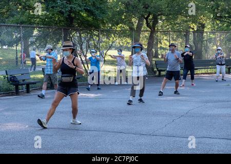 Uomini e donne di varie età ed etnie frequentano una lezione di Tai Chi al mattino, distanziando sociale e indossando maschere chirurgiche. In Queens, New York City. Foto Stock