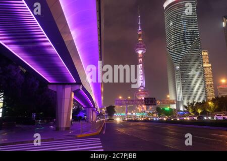 Scena notturna della moderna Shanghai Pudong. Autostrada sotto il cavalcavia viola brillante. La famosa torre e gli edifici della TV Oriental Pearl Foto Stock