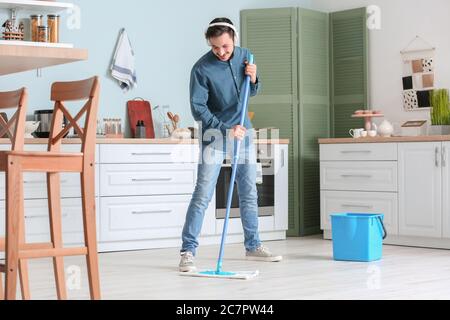 Bel pavimento per la pulizia di un giovane uomo in cucina Foto Stock