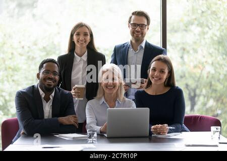 I colleghi multi nazionali si siedono in posa per la fotocamera Foto Stock