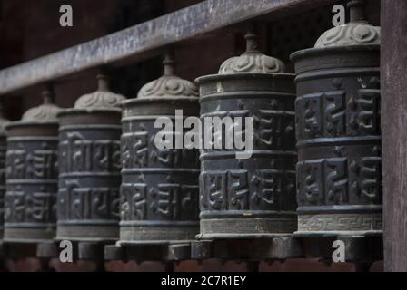 Fila di ruote buddiste di preghiera fotografate a Kathmandu, Nepal. Foto Stock