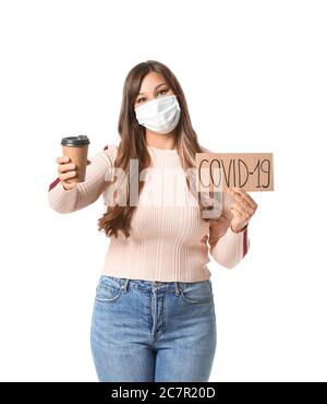 Giovane donna in maschera protettiva e con tazza di caffè su fondo bianco. Concetto di epidemia di coronavirus Foto Stock