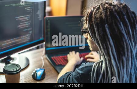 Moderna giovane programmatore femminile sta scrivendo codice programma su un portatile a casa. Lavoro remoto nella professione IT. Il concetto di sviluppo software. Foto Stock