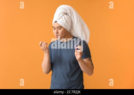 Divertente uomo asiatico facendo manicure su sfondo a colori Foto Stock