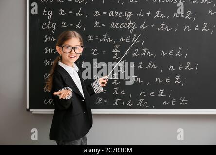 Carina piccola scolaretta vicino a lavagna in classe Foto Stock