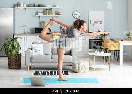 Giovane donna incinta a praticare yoga a casa Foto Stock