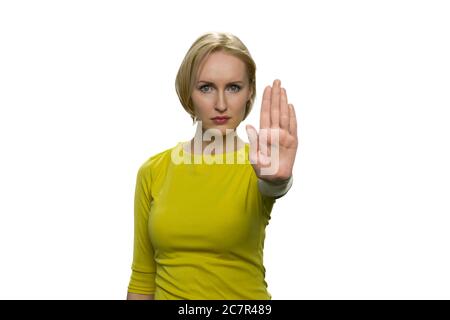 Giovane donna in tultleneck giallo facendo gesto di stop con la sua palma su sfondo bianco. Foto Stock