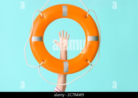 Mano umana con lifebuoy su sfondo a colori Foto Stock