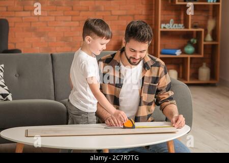 Padre e figlio prendono misure di tavola di legno a casa Foto Stock