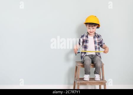 Bambino con nastro di misurazione su sfondo grigio Foto Stock