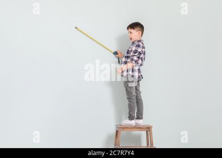 Bambino con nastro di misurazione su sfondo grigio Foto Stock