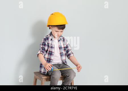 Bambino con nastro di misurazione su sfondo grigio Foto Stock