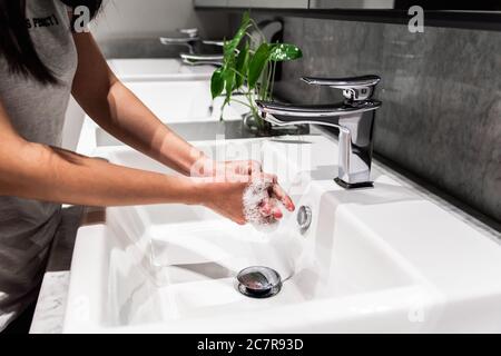 Giovani donne asiatiche lavano la mano con sapone nel rubinetto. Nuova normale, prevenzione del coronavirus. Foto Stock