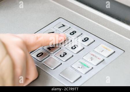 Primo piano di un dito maschio che preme i tasti su un Tastiera ATM Foto Stock