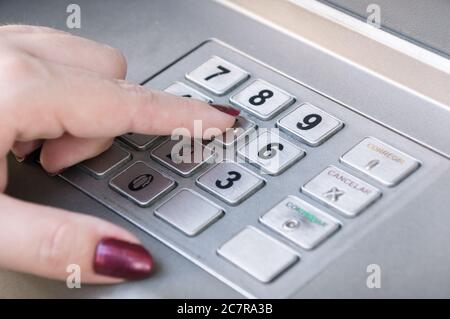 Primo piano di un dito femminile che preme i tasti su un Tastiera ATM Foto Stock