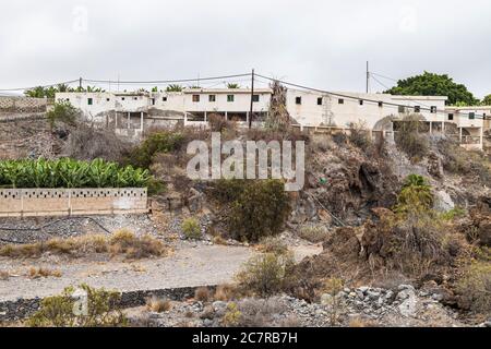 Schiera a schiera di vecchie case operaie finca derelict sopra un barranco a Playa San Juan, Tenerife, Isole Canarie, Spagna Foto Stock