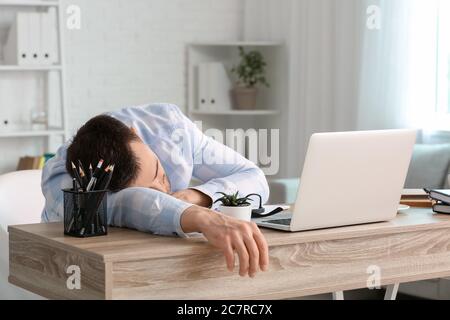 Giovane addormentato durante il lavoro in ufficio. Concetto di privazione del sonno Foto Stock