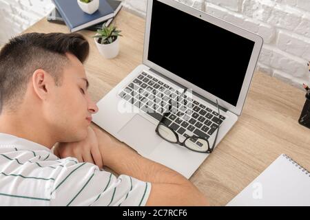 Giovane addormentato durante il lavoro in ufficio. Concetto di privazione del sonno Foto Stock