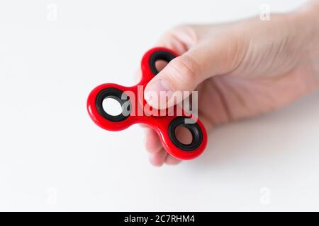 primo piano di fidget spinner in mano femminile su bianco Foto Stock