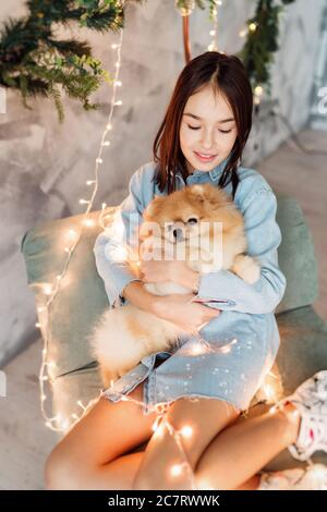 Bambina ragazza sta tenendo il cucciolo sulle sue mani vicino all'albero di Natale Foto Stock