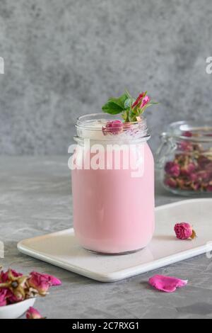 Latte di luna di rosa in vaso di muratore su sfondo grigio. Primo piano. Ayurveda bevanda calda. Bello in caso di insonnia. Foto Stock