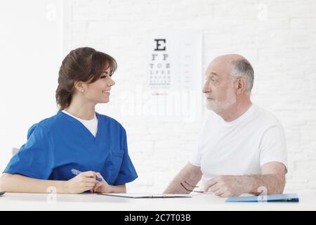 Medico che fa il test di visione per nuovi occhiali per il paziente anziano Foto Stock