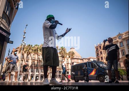 Malaga, Spagna. 19 luglio 2020. Un artista si esibisce indossando una maschera di fronte al camion della polizia in Calle Marquès de Larios durante la protesta. Si è protestato per la regolarizzazione dei migranti che vivono in Spagna, per quanto riguarda la loro situazione legale o il loro status nel paese. I manifestanti chiedono documenti legali per circa 600.000 migranti che vivono in una situazione irregolare. Inoltre, chiedono il diritto di accedere all'istruzione legale, ai servizi sanitari e ai posti di lavoro legali. Credit: SOPA Images Limited/Alamy Live News Foto Stock