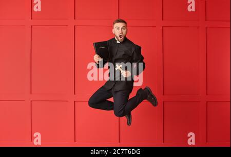 Saltando giovane sacerdote su sfondo a colori Foto Stock