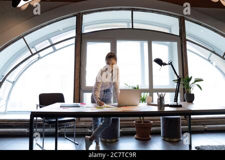 Dipendente femminile concentrato prepara il rapporto in ufficio Foto Stock