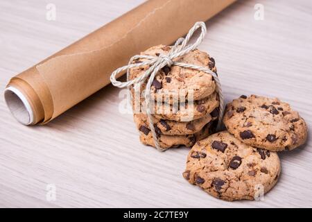 primo piano di biscotti al cioccolato e carta pergamena su sfondo di tavola di legno Foto Stock