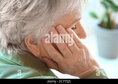 Senior donna che soffre di mal di testa a casa Foto Stock