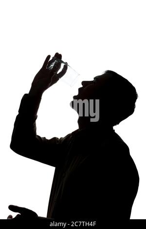 Giovane uomo che beve un bicchiere di acqua frizzante, senza acqua - silhouette Foto Stock