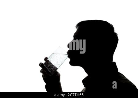 Giovane uomo che beve un bicchiere di acqua frizzante - silhouette Foto Stock