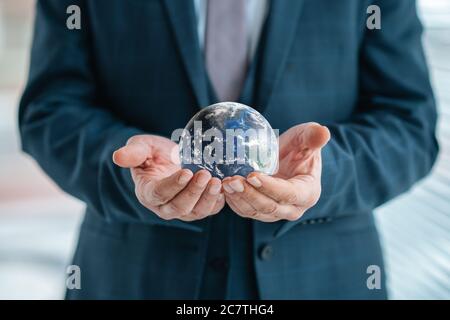 L'uomo d'affari ha una sfera mondiale, concetto di essere connesso e governare il mondo, dominio globale. Elementi di questa immagine forniti dalla NASA Foto Stock