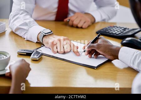 un manager di concessionaria di aiuto fornisce le informazioni necessarie e le istruzioni ai clienti, spiega tutto prima di firmare un contratto. primo piano foto di Foto Stock