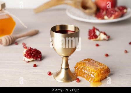 Calice sacramentale con vino, miele e melograno a tavola. Rosh Hashanah (Capodanno ebraico) celebrazione Foto Stock