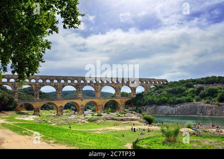 REMOULINS, FRANCIA - 19 LUGLIO 2014: I turisti hanno un riposo sulla riva del fiume Gardon sotto un vecchio acquedotto romano Pont du Gard. La Gorge du Gardon è un Foto Stock