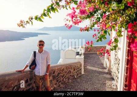 L'uomo viaggiante di Santorini cammina a Thera con i fiori, la Grecia godendo del paesaggio della Caldera. Turismo, viaggio, vacanza estiva Foto Stock