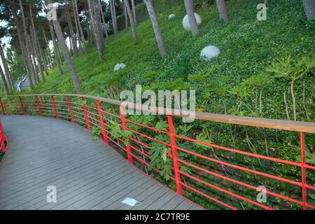 Ponte rosso situato all'esterno del Parco Nazionale . Green Leaf Park. Ci sono luci bianche rotonde a terra . Strada ponte nel parco . Foto Stock